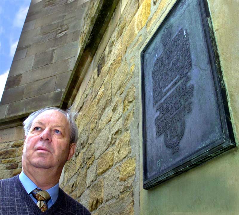 John Chandler beside the war memorial plaque at St Mark's Church, Natland
